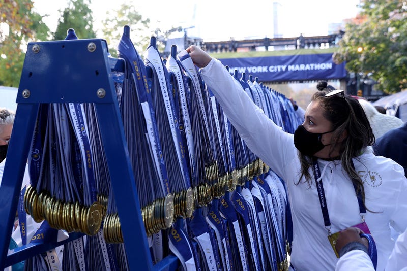Volunteers hang participation medals just after the finish line for runners of the 2021 TCS New York City Marathon in Central Park on November 07, 2021 in New York City.