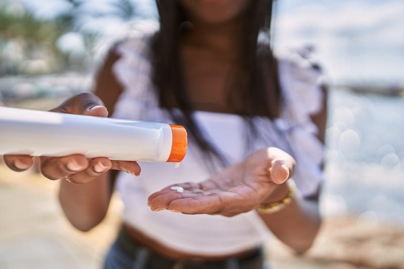 Young african american girl using sunscreen lotion at the beach.