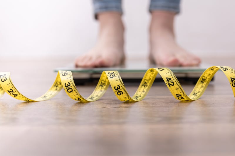 Person stands on a scale with a tape measurer in front of it