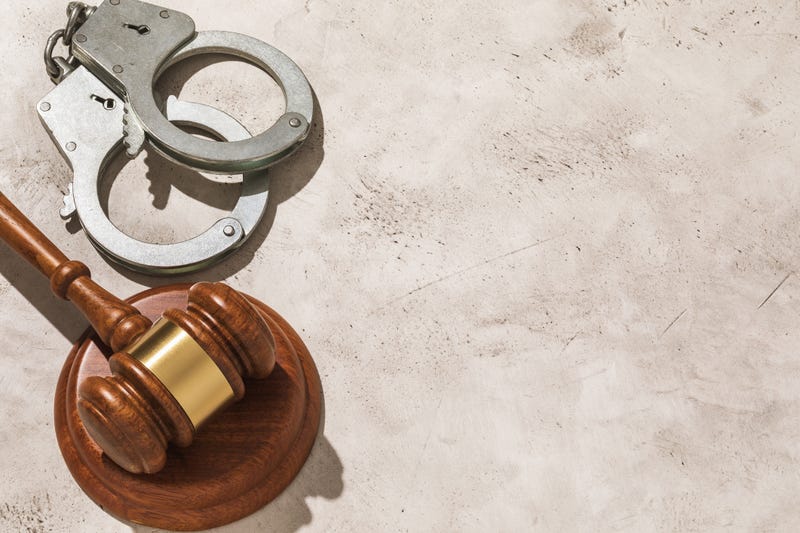 Judge gavel and handcuffs on the left side of the table with copy space, top view