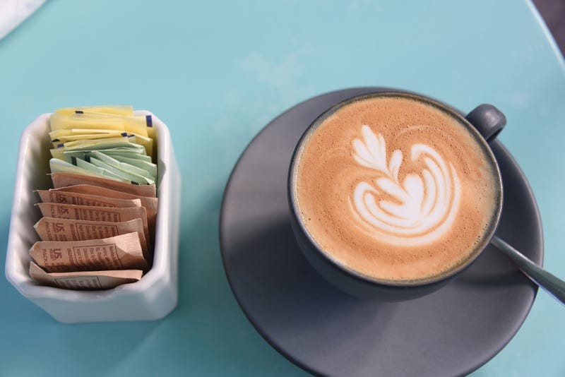 Artificial sweeteners next to a cup of coffee.