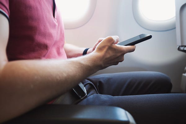Man using a smartphone while on an airplane