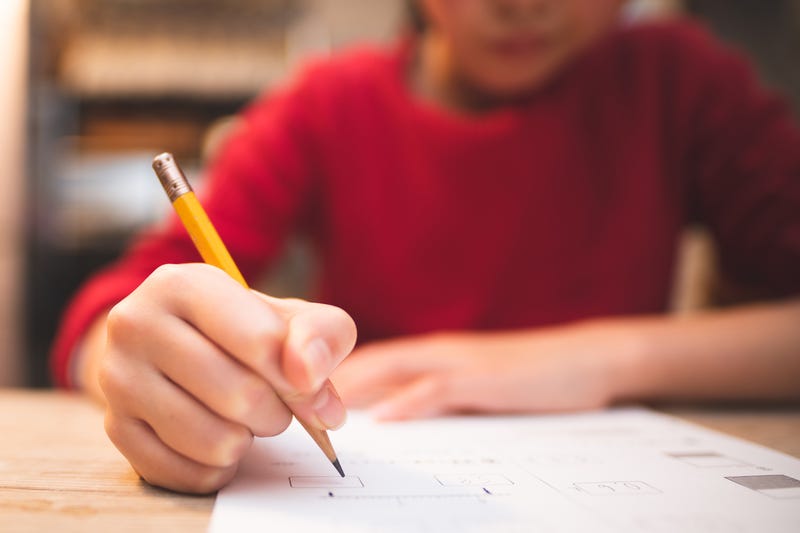 A child writes at his desk in class.