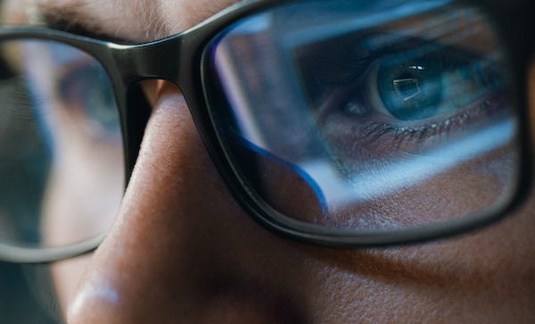 Close up of computer screen reflecting off eyeglasses