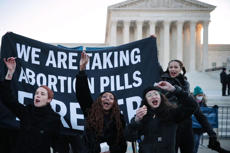 Lila Bonow, Alana Edmondson and Aiyana Knauer prepare to take abortion pill while demonstrating in front of the U.S. Supreme Court as the justices hear hear arguments in Dobbs v. Jackson Women's Health, a case about a Mississippi law that bans most abortions after 15 weeks, on December 01, 2021 in Washington, DC. With the addition of conservative justices to the court by former President Donald Trump, experts believe this could be the most important abortion case in decades and could undermine or overturn Roe v. Wade. (Photo by Chip Somodevilla/Getty Images)