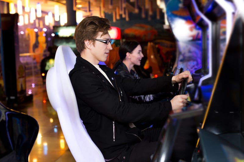 Two people in an arcade playing a racing car game