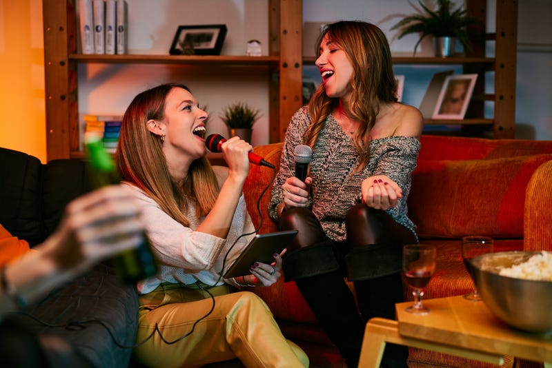 Happy girls sitting at home and singing a duet