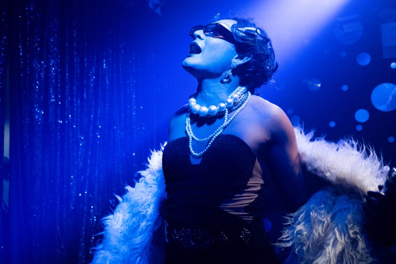 drag queen on stage with feather boa