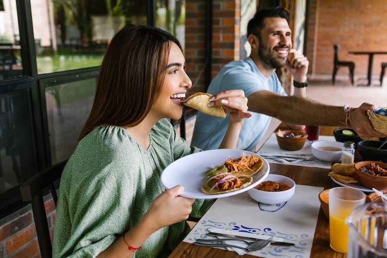 Woman eating tacos at a restaurant with friends