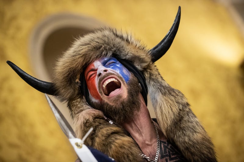 jacob chansley on jan 6 with his face painted, his bull horns, and his flag which appears to be sharpened at the tip