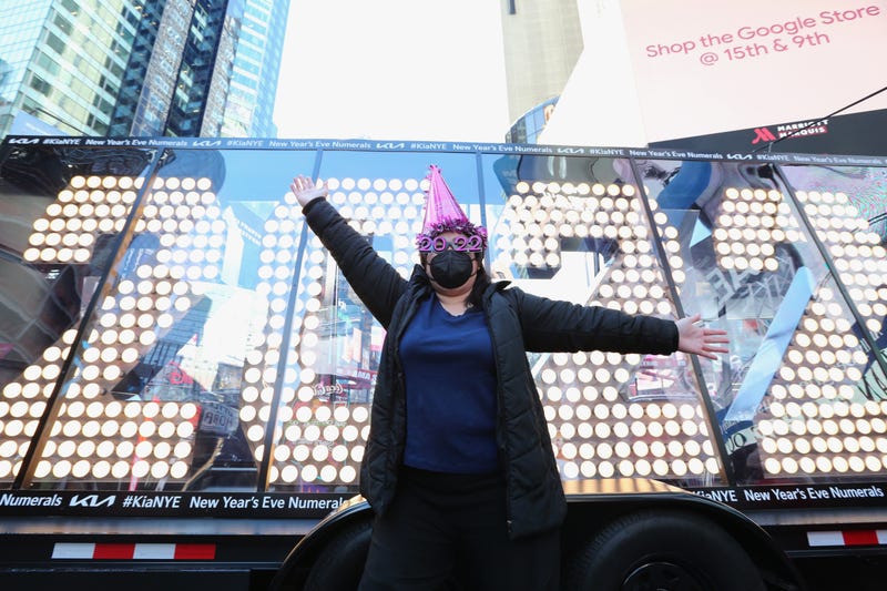 A person wearing festive new year's hat and glasses poses at the 2022 New Year's Eve numerals as they arrive in Times Square on December 20, 2021 in New York City. (Photo by Rob Kim/Getty Images)