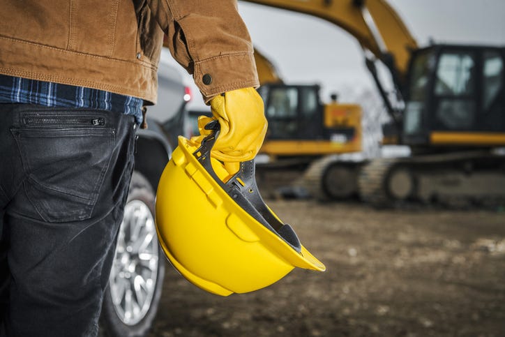 Blue collar worker holding a construction helmet.