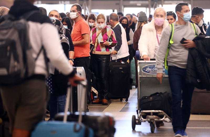 FILE - Travelers gather in the international terminal at Los Angeles International Airport (LAX) amid a surge in omicron variant cases on December 21, 2021 in Los Angeles.