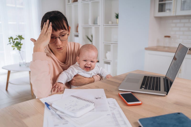 Unhappy frustrated single mother with crying children trying to work at home or solve family financial troubles, tired of balancing motherhood and work, doesn't have money to pay domestic bills