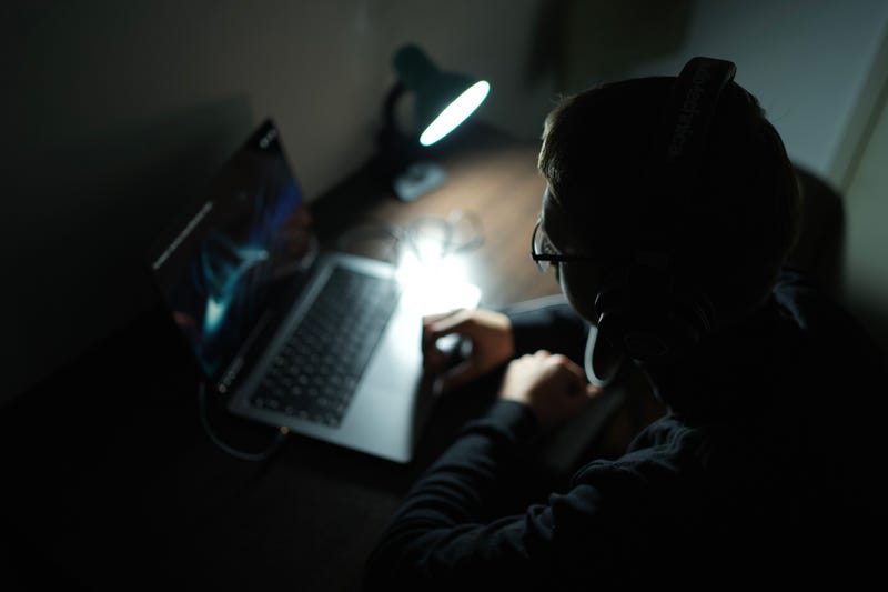 teen boys sits at laptop in dark room