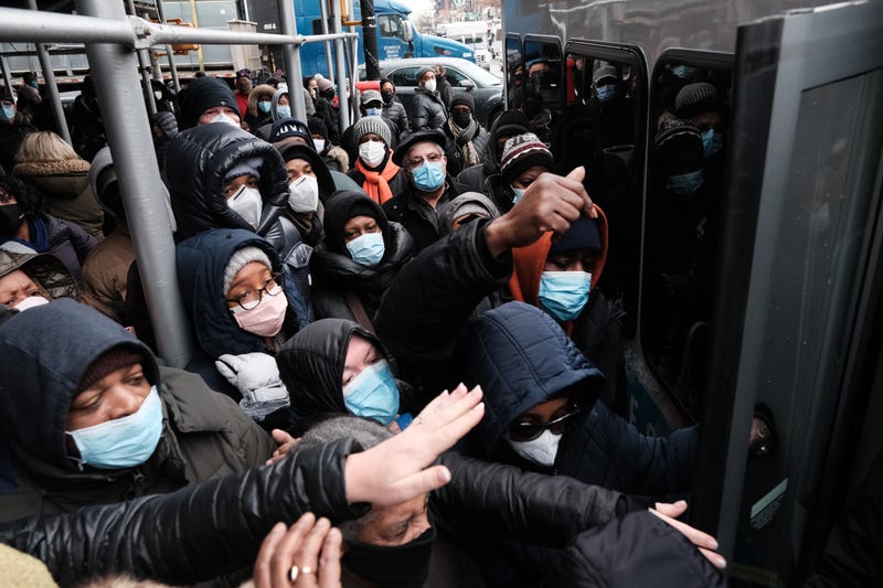 People form a large crowd as they attempt to receive COVID-19 testing kits from city workers distributing the kits along Flatbush Avenue in Brooklyn on Dec. 24, 2021