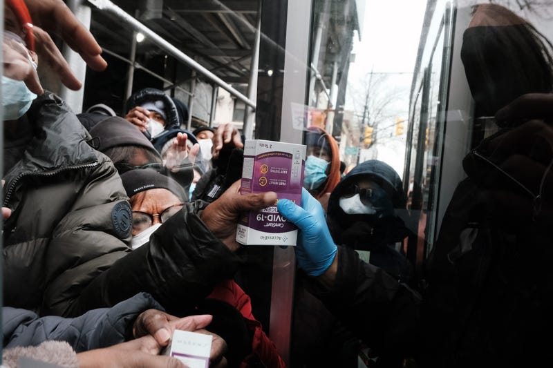 People form a large crowd as they attempt to receive COVID-19 testing kits from city workers distributing the kits along Flatbush Avenue in Brooklyn on Dec. 24, 2021