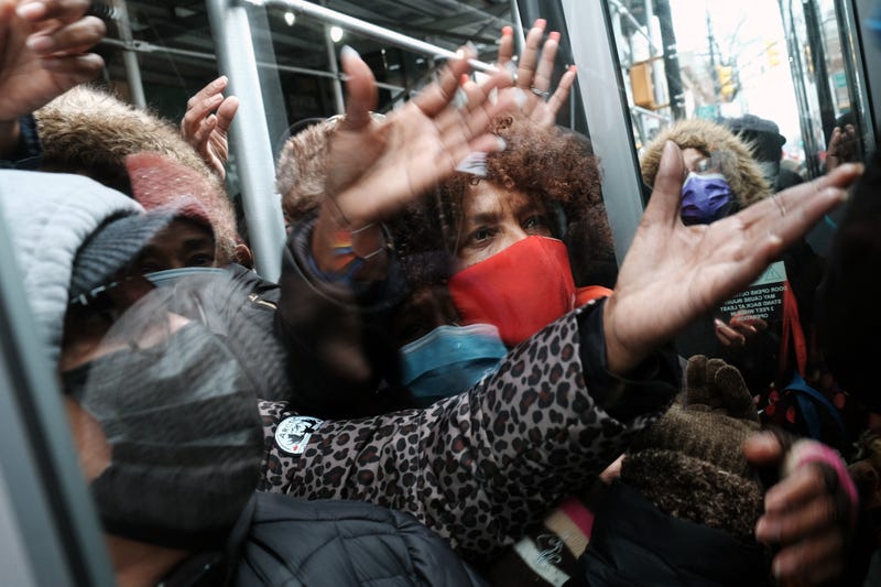 People form a large crowd as they attempt to receive COVID-19 testing kits from city workers distributing the kits along Flatbush Avenue in Brooklyn on Dec. 24, 2021
