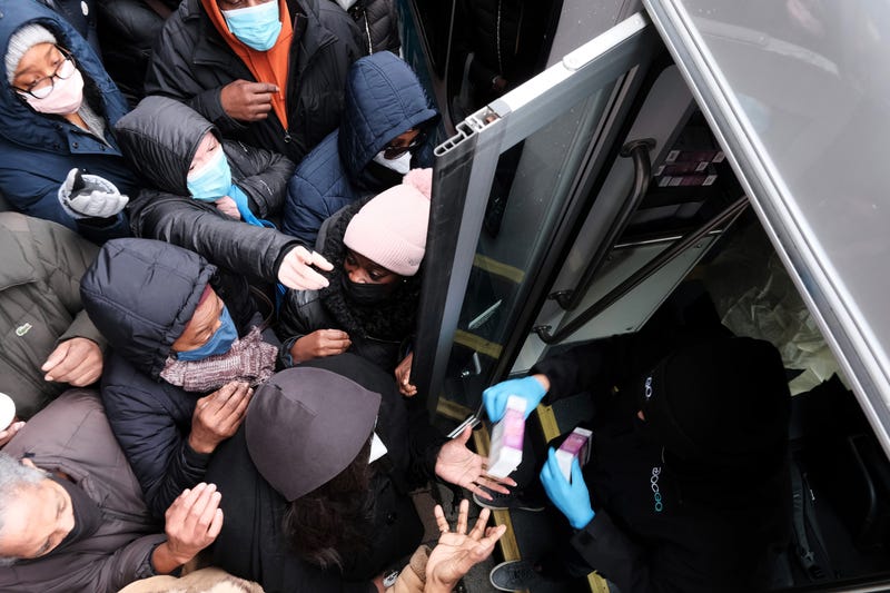People form a large crowd as they attempt to receive COVID-19 testing kits from city workers distributing the kits along Flatbush Avenue in Brooklyn on Dec. 24, 2021