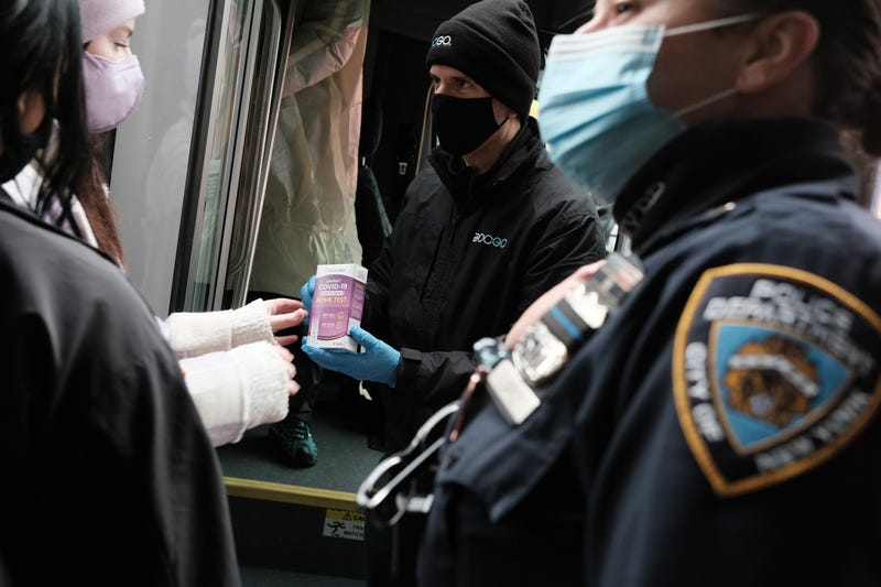People form a large crowd as they attempt to receive COVID-19 testing kits from city workers distributing the kits along Flatbush Avenue in Brooklyn on Dec. 24, 2021