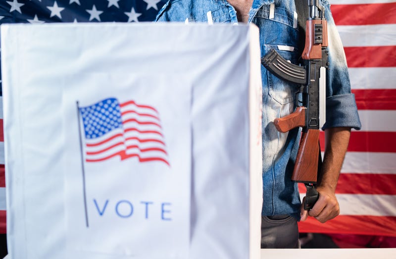 Man with a gun at a voting booth, in front of an American flag.