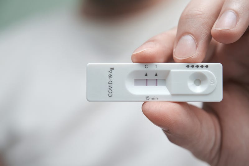 Hand holding a positive antigen test for COVID-19.