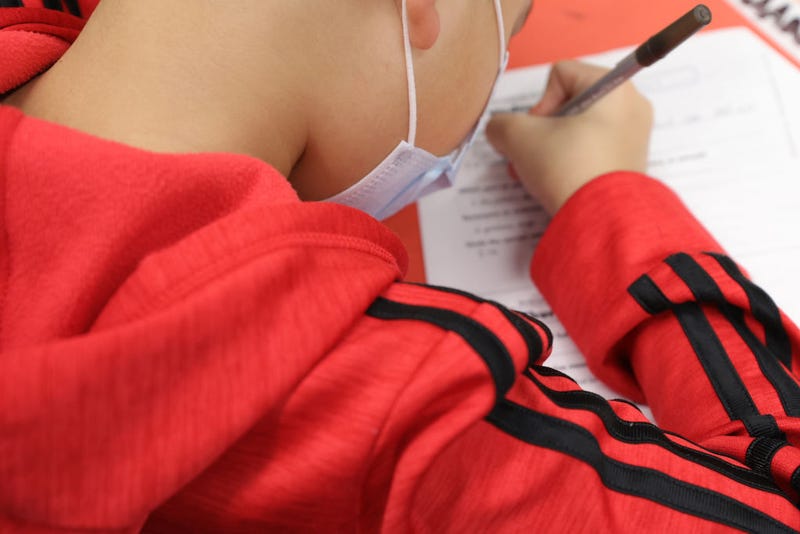 A masked student doing work at school