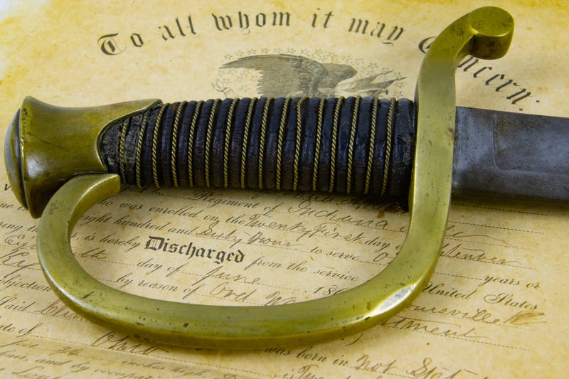 Old Saber lying on a historic document of Union Army discharge Certificate from 1863 with focus on Handle