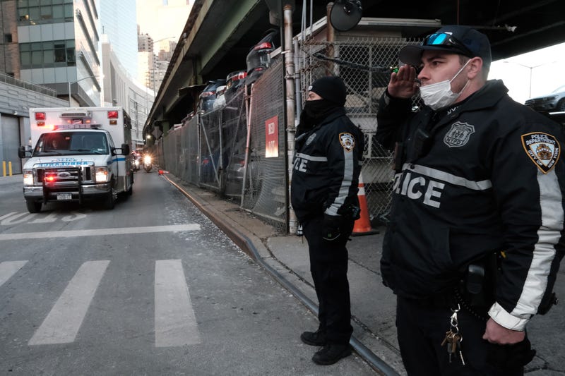 Police officers pause as the body of NYPD officer Wilbert Mora is transferred in an ambulance from NYU Langone Hospital to the medical examiner's office in Kips Bay on Jan. 25, 2022