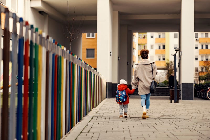 stock image of a woman holding a baby's  hand as they walk away from the camera