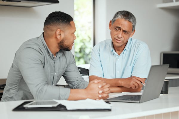 Man and his father working on a laptop at home