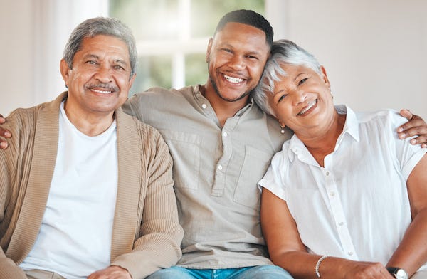 Adult son posing with his mom and dad