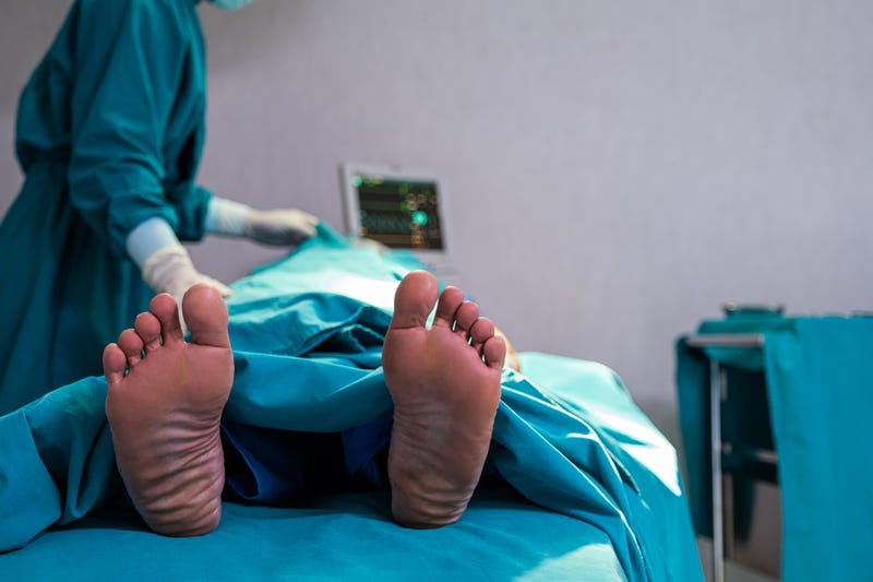 Selective focus at feet of pass away patient while doctor covering face inside of the surgery operation room in the hospital. Illness and death concept.