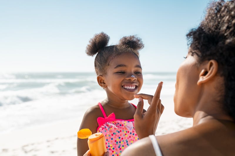 Mother applies sunblock to little girl