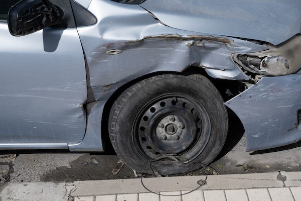 Car with damaged tire next to a curb