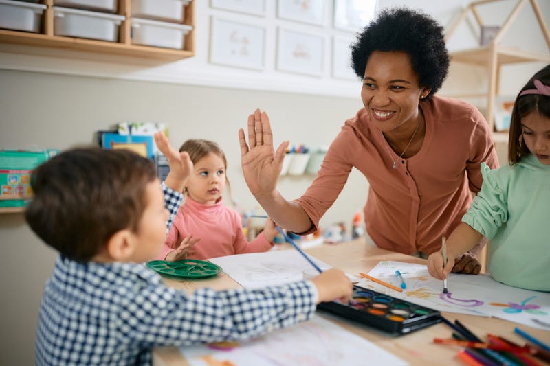 FILE: A small boy giving high-five during art class at kindergarten.