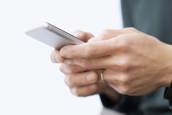 Married man wearing wedding ring typing on phone