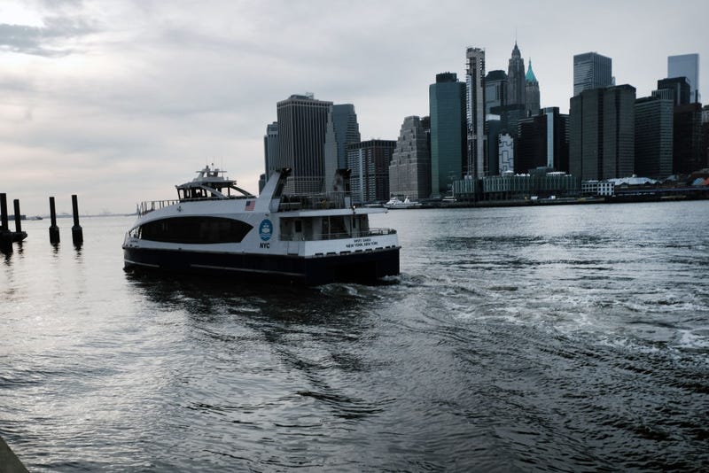 A ferry arrives into a dock as the Manhattan skyline is seen across the East River on February 16, 2022 in the Brooklyn borough of New York City.