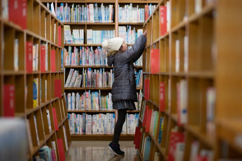 girl picking book from library