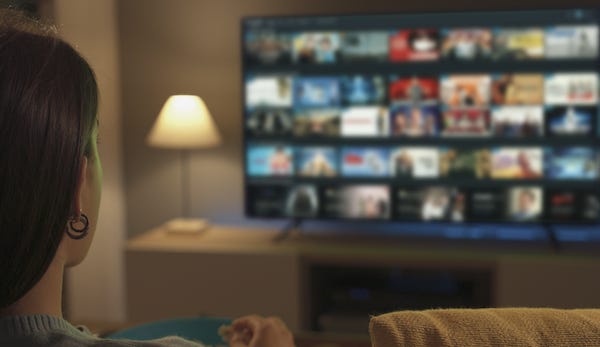 Young woman watching video on demand on her TV