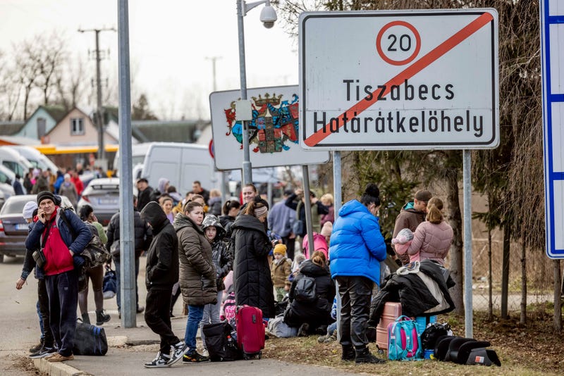 People wait with their belongings at the Tiszabecs-Tiszaujlak border crossing as they flee Ukraine on February 25, 2022 in Tiszabecs, Hungary