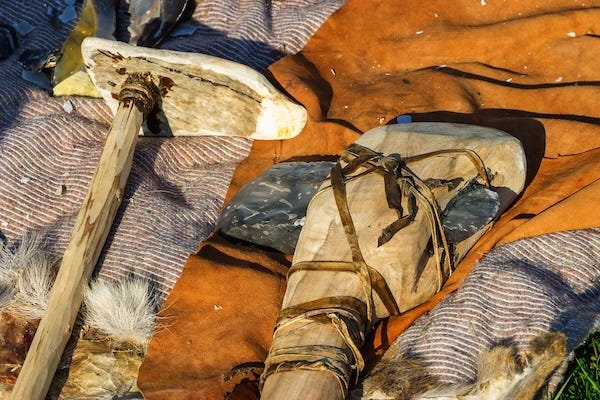Flint axe and bone club resting on blankets