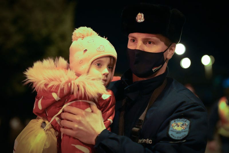 A Hungarian police officer carries a refugee child across the dark tracks at Zahony train station as the influx of refugees from Ukraine continues through the night on March 03, 2022 in Zahony, Hungary. Over one million refugees from Ukraine have now fled into neighbouring countries such as Hungary, forming long queues at border crossings, after Russia began a large-scale attack on Ukraine on February 24, 2022. (Photo by Christopher Furlong/Getty Images)