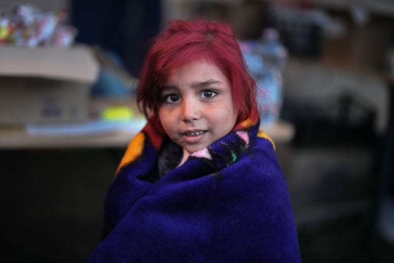 A refugee girl from Ukraine uses a blanket to keep warm.