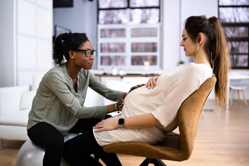 Peaceful Pregnant Woman Having A Relaxing Massage From African Female Therapist At Home