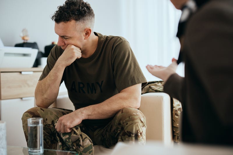 vet looking downwards, distressed, talking to a social worker