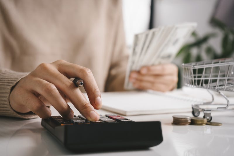 woman with calculator holding stack of cash