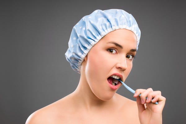 Woman wearing a shower cap brushing her teeth