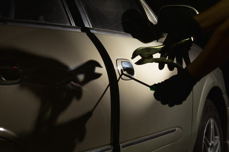 Car thief using a tool to break into a car