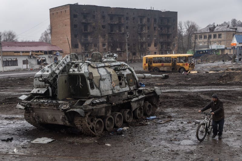 A man pushes his bike through mud and debris past a destroyed Russian tank in front of the central train station that was used as a Russian base on March 30, 2022 in Trostyanets, Ukraine.